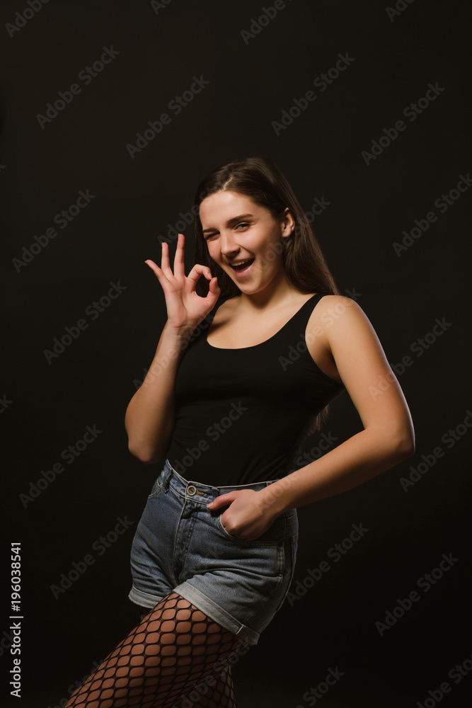Model test with funny emotional model in black shirt and jeans shorts posing in the shadows Model test with funny emotional model in black shirt and jeans shorts posing in the shadows