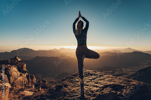 Canvastavla Woman does yoga exercises on cliff on Mount Sinai against background of sunrise
