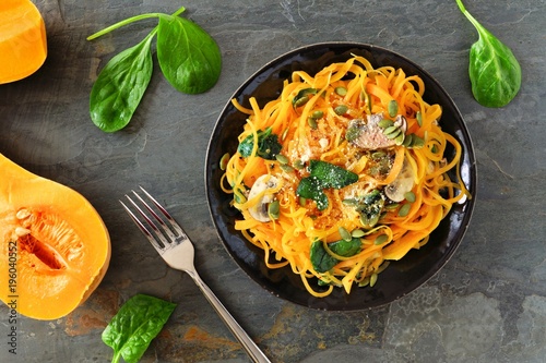 Butternut squash spirilized noodles with spinach and pumpkin seeds on dark slate background, Healthy eating concept. Top view, table scene.