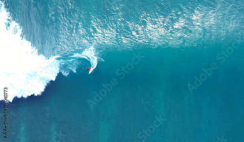TOP DOWN: Unrecognizable pro surfer riding a stunning blue ocean wave in the sun