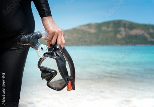 Diving goggles and snorkel gear in hand near beach photo