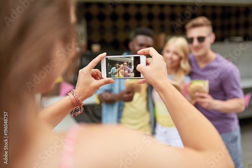 woman photographing friends eating at food truck