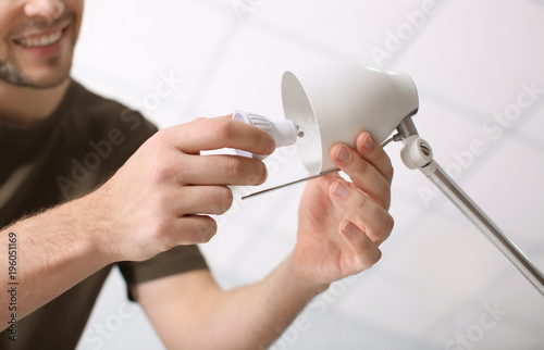 Man changing light bulb in lamp at home