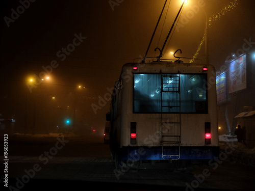 White trolleybus driving dangerously in the fog at night