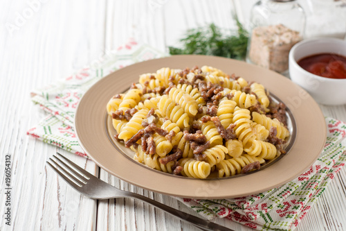 Fusilli pasta with minced meat and onion in navy-style on white wooden table. Makarony po-flotski, Russian dish.