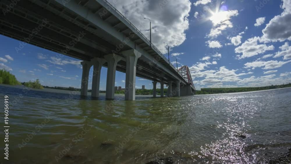 Timelapse view of beautiful clouds in blue sky, sun is shining. Suspension Bridge Bugrinsky over the Ob river in Novosibirsk, Siberia, Russia in sunny day time lapse. Timelapse view of beautiful clouds in blue sky, sun is shining. Suspension Bridge Bugrinsky over the Ob river in Novosibirsk, Siberia, Russia in sunny day time lapse.