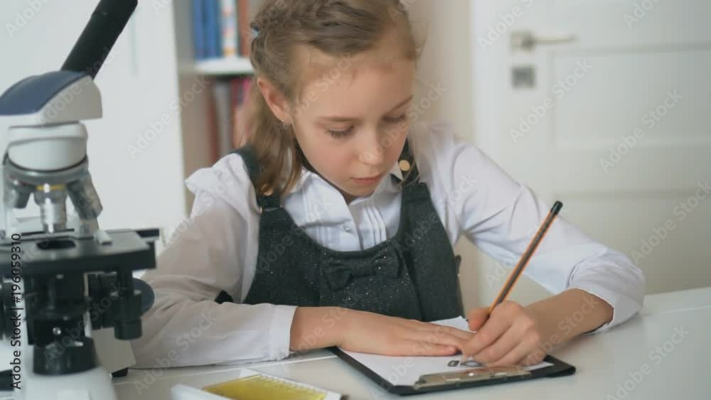 Little girl in science class with microscope on the table. Little girl in science class with microscope on the table.