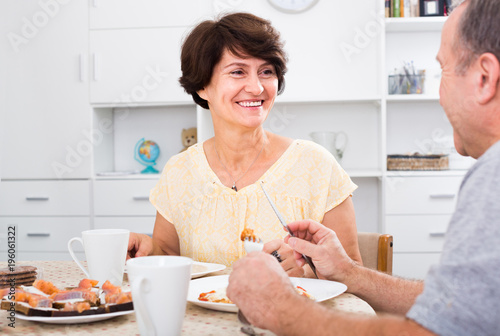 senior woman eating with man at home .
