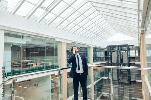 Enthusiastic Business man walking while talking on mobile phone on his way to work