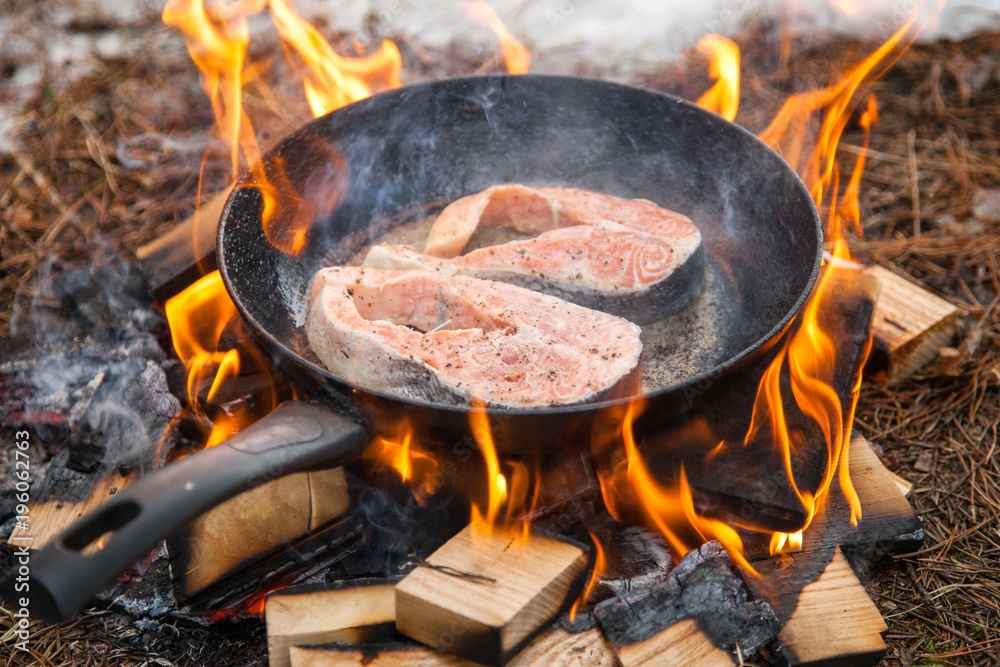 Preparation of steak from red fish in winter in the forest at the stake. Preparation of steak from red fish in winter in the forest at the stake.