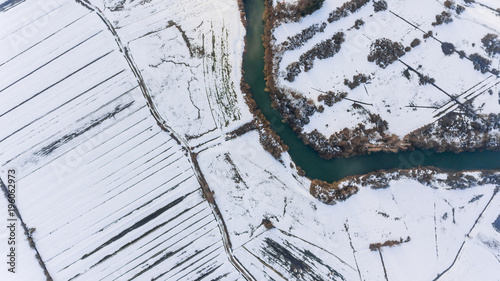 Aerial view riverbend passing snow covered fields. photo