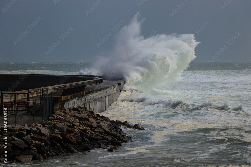 Fototapeta premium Big storm waves reach a breakwater structure in a pier in the Atlantic coastline. Cascais Portugal
