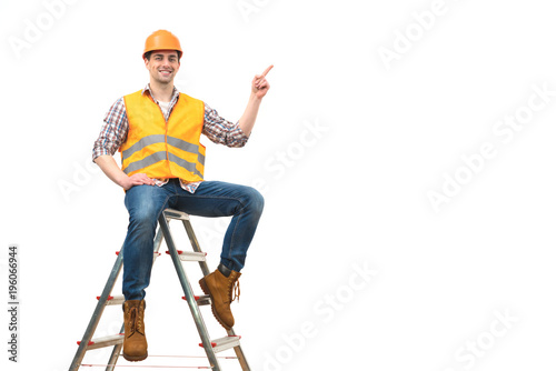 Tableau sur toile The happy builder on the ladder gesturing on the white background