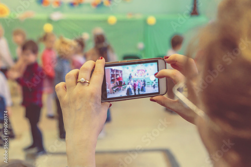 woman taking a picture of children on the phone in kindergarten
