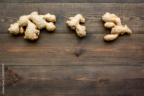Whole ginger roots on dark wooden background top view space for text