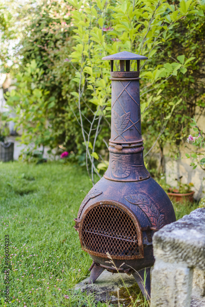 Fototapeta premium Decorative bronze wooden stove in a garden, barbecue with grill .