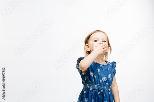 Portrait of a cute little preschool girl with hand on mouth on white background