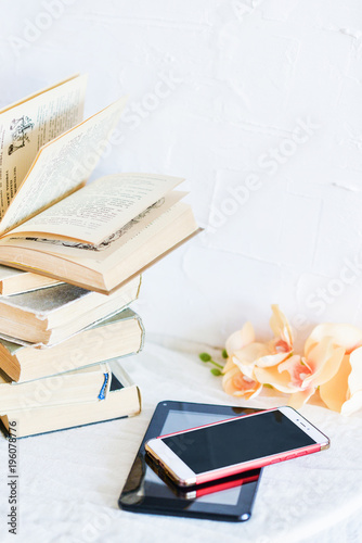 a stack of old books, phone, and e-book, concept of the development of technology, gadgets and love to read on a white background