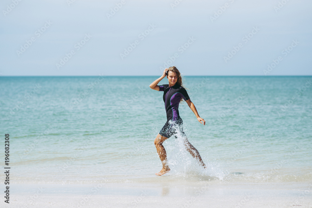 Beautiful woman in wetsuit on the idyllic beach Beautiful woman in wetsuit on the idyllic beach