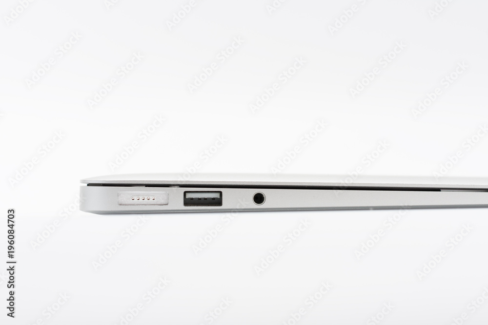 Part of closed modern new laptop with ports on white background, close up, side view. Part of closed modern new laptop with ports on white background, close up, side view.