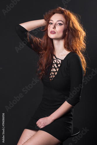red-haired model posing in studio on dark background