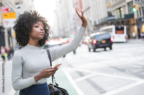 Foto Woman hailing taxi cab or ride share car service in New York