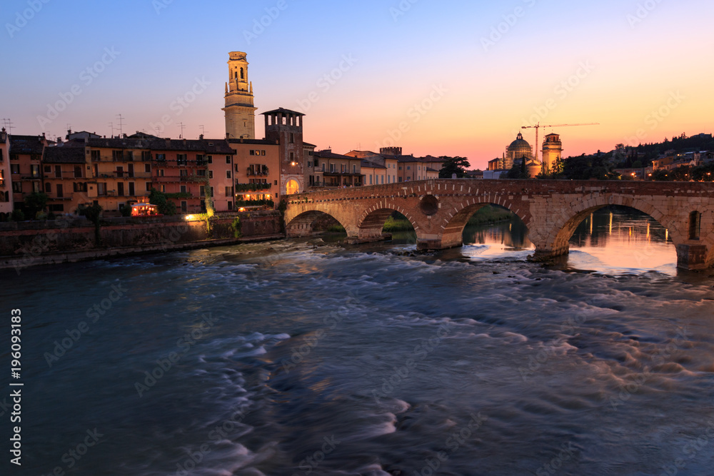 Verona cityscape with Ponte Pietra on Adige river with historical buildings in the evening