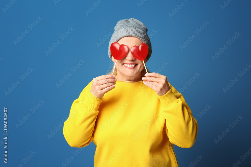 Portrait of stylish female pensioner with lollipops on color background