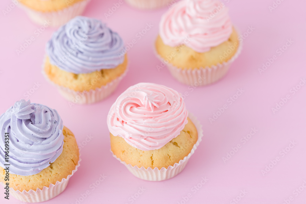 Violet and pink cupcakes with buttercream standing on pastel pink background.