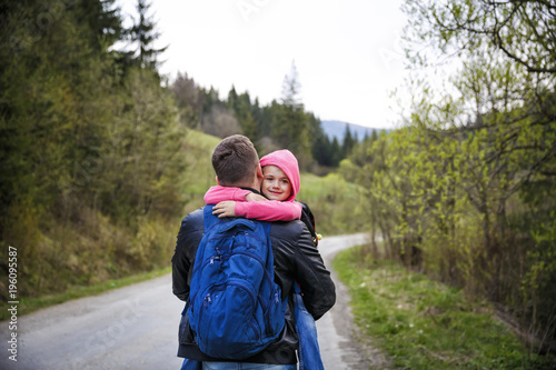 Young father and his adorable little daughter hiking in mountains in beautiful sunny day