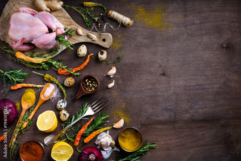 Raw chicken,herbs and spices on cutting board. Food ingredients.