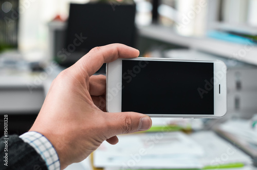 Businessman using mobile phone on light background for photo or video. Writing text, checking calls, reading messages. Close up picture of communication technology device