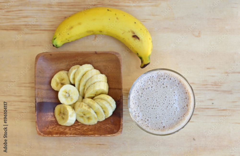 Banana smoothie and fresh banana on wooden background. Top view.