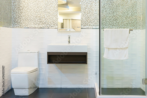 Bathroom interior with white walls, a shower cabin with glass wall, a toilet and sink