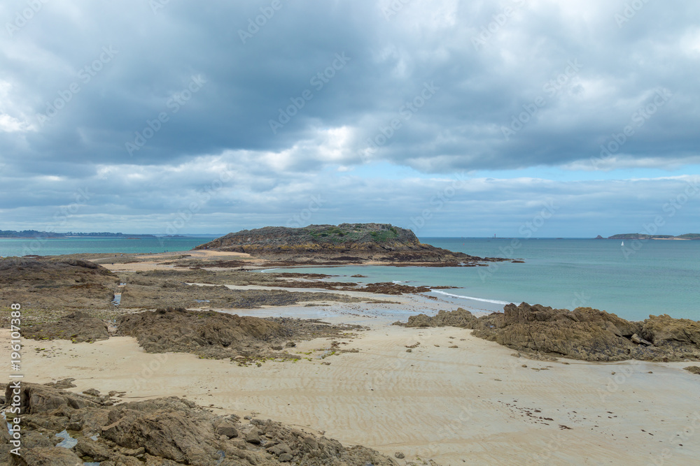 Northern european beach with small island, rocks, stones and cloudy cold windy day Northern european beach with small island, rocks, stones and cloudy cold windy day