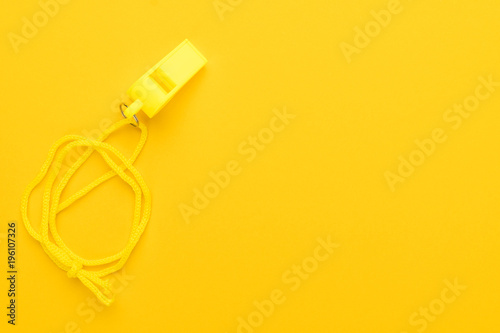 plastic referee whistle on the yellow background with copy space