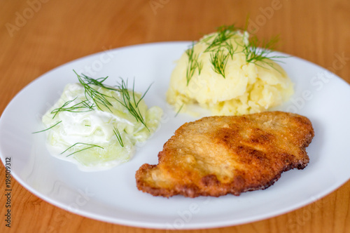 Polish kotlet schabowy (pork chop) with mizeria and mashed potatoes. photo