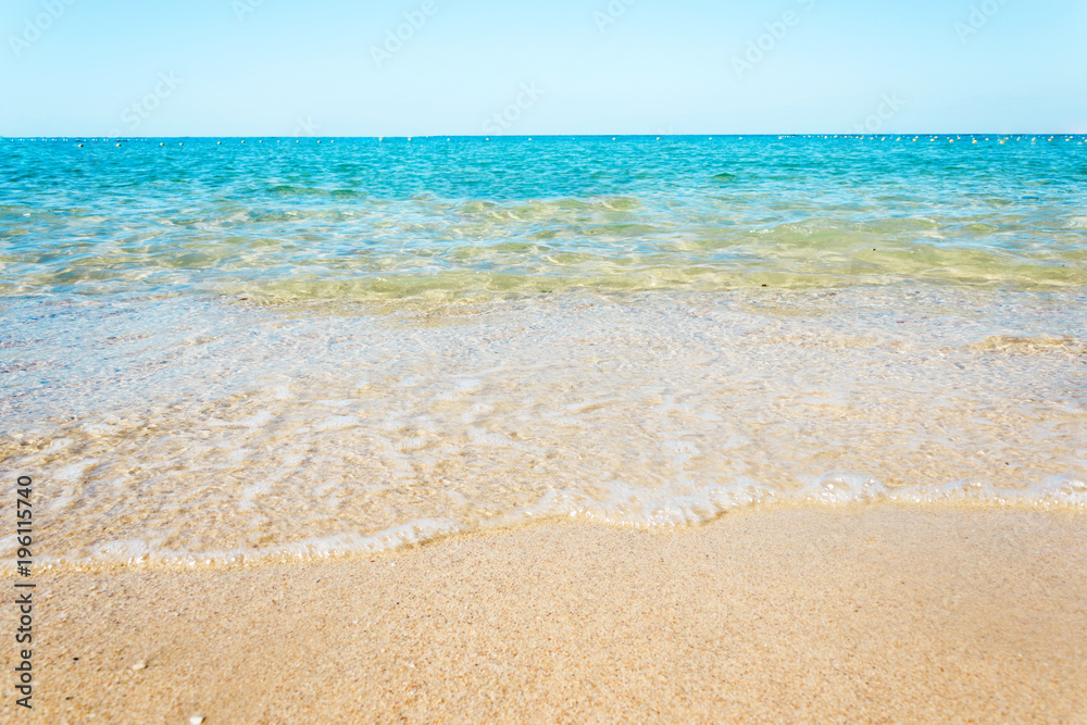 Soft waves with foam of blue ocean on the sandy beach