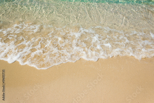 Soft waves with foam of blue ocean on the sandy beach