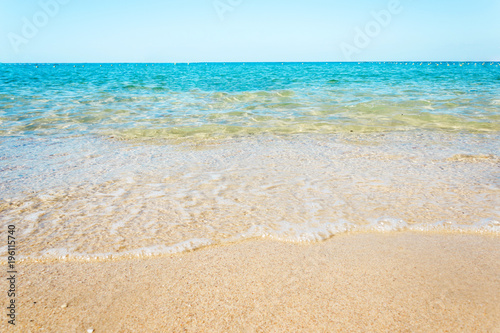 Soft waves with foam of blue ocean on the sandy beach