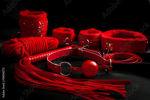 Obraz na płótnie Sexual kink, erotic games and human sexuality concept with complete red sex toy kit set (ball gag, cuffs, rope, flogger, collar and leash) for BDSM fantasy play and bondge restraints on black silk w salonie