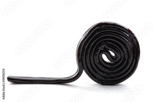 Sugar confectionery sweets and sweet candy concept with one black licorice or liquorice wheel or spiral isolated on white background
