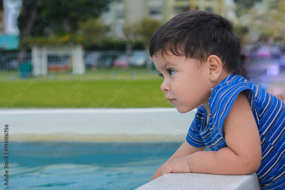 Serious latin little boy close to the water pool. Serious latin little boy close to the water pool.