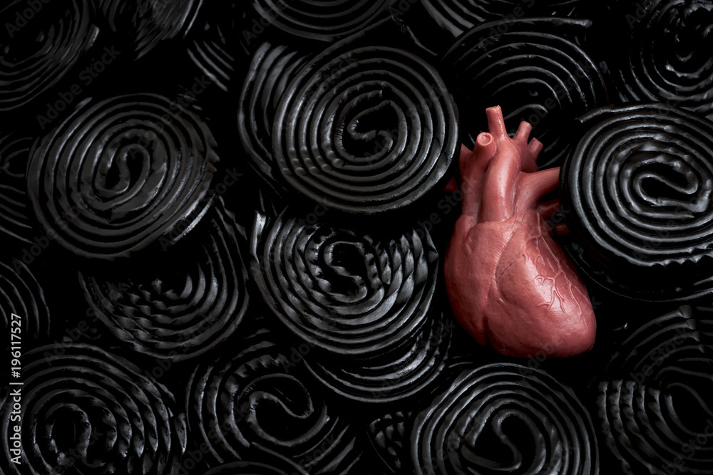 Black licorice is bad for your health concept with a heart buried in