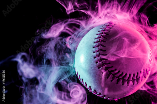 White baseball ball in multi-colored red smoke from a vape on a black isolated background photo