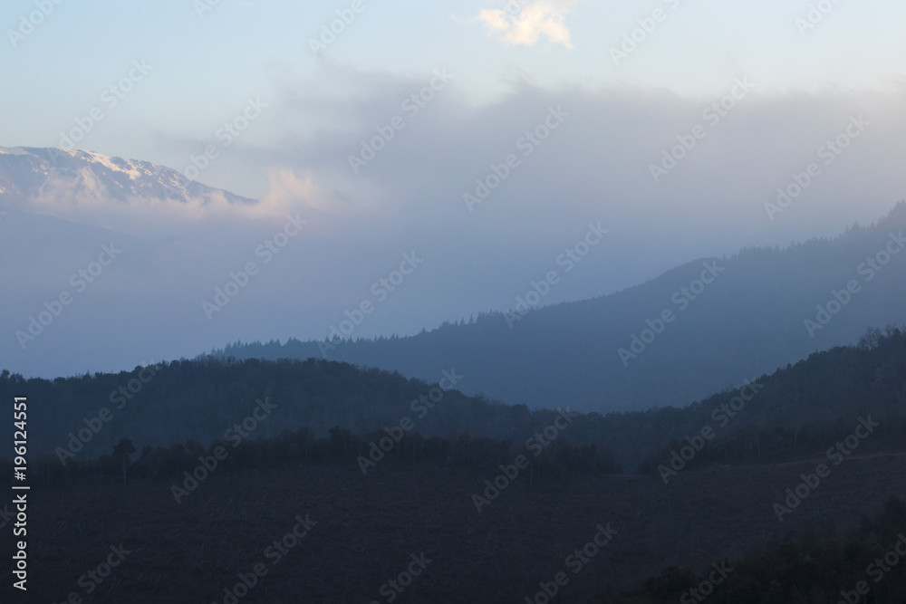 Fototapeta premium Foggy mountain crest landscape on a blue sky sunset