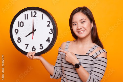 Young Asian woman point to a clock.