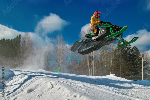 Big green Sport snowmobile jump. Cloud of snow dust from under snowmobile tracks. Concept extreme rest. photo