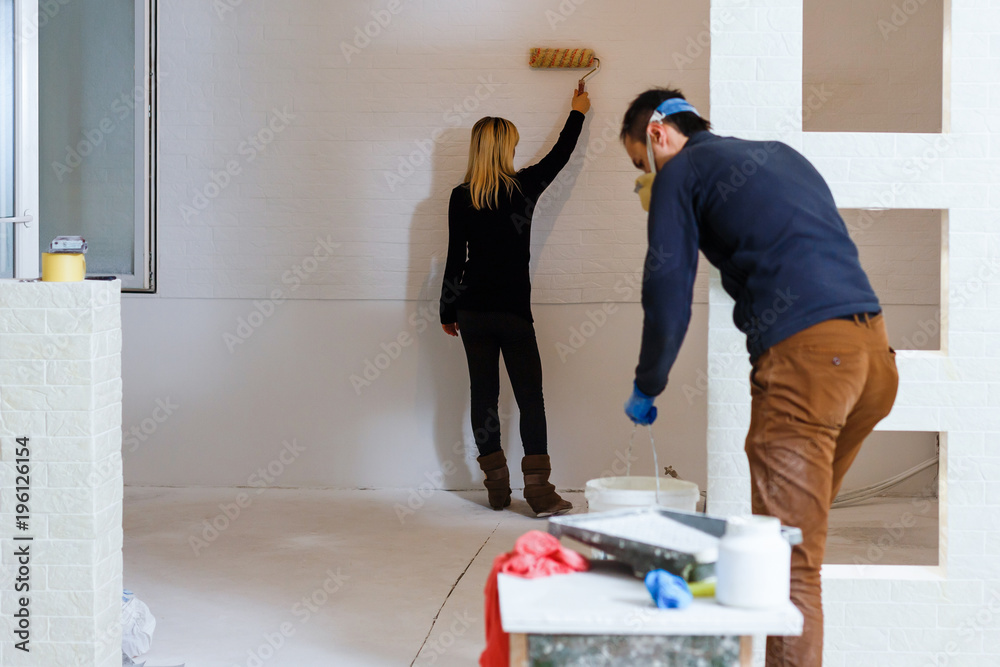 Portrait of young couple painting the wall in the apartment Portrait of young couple painting the wall in the apartment