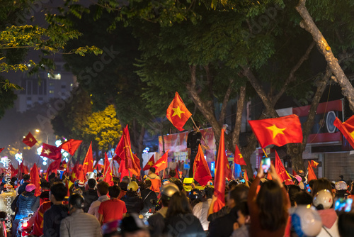 Crowd of Vietnamese football fans down the street to celebrate the win after soccer, with a lot of Vietnamese flags raising high